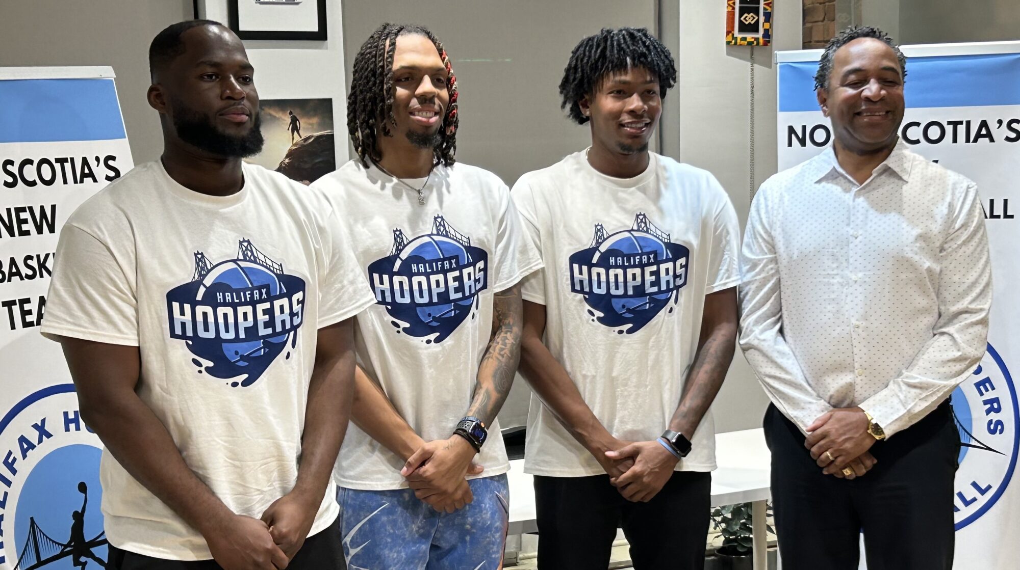 Three players wearing Halifax Hoopers T-shirts, stand with their coach