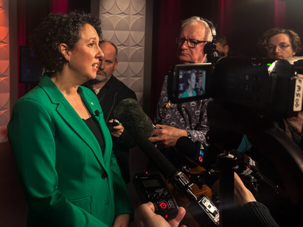 A woman answering questions from journalists in front of microphones and cameras