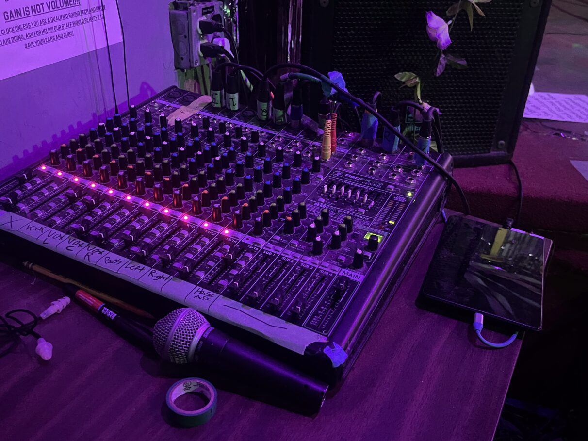 Soundboard and microphone in dim purple lighting.