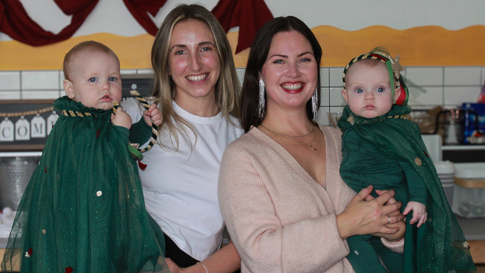 the two organizers standing side by side, holding their babies.