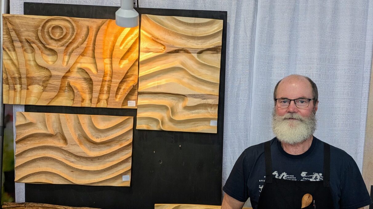 Andrew Tubman stands beside some of his wall art pieces.