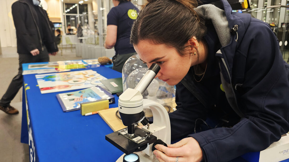 A woman peering into a microscope on a table.