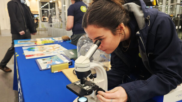 A woman peering into a microscope on a table.