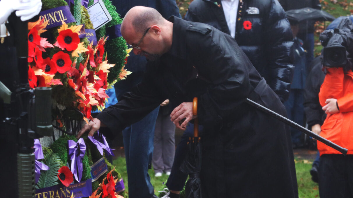 a man lays a wreath on a cenotaph