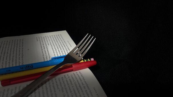 A fork and some pens laying on a book.