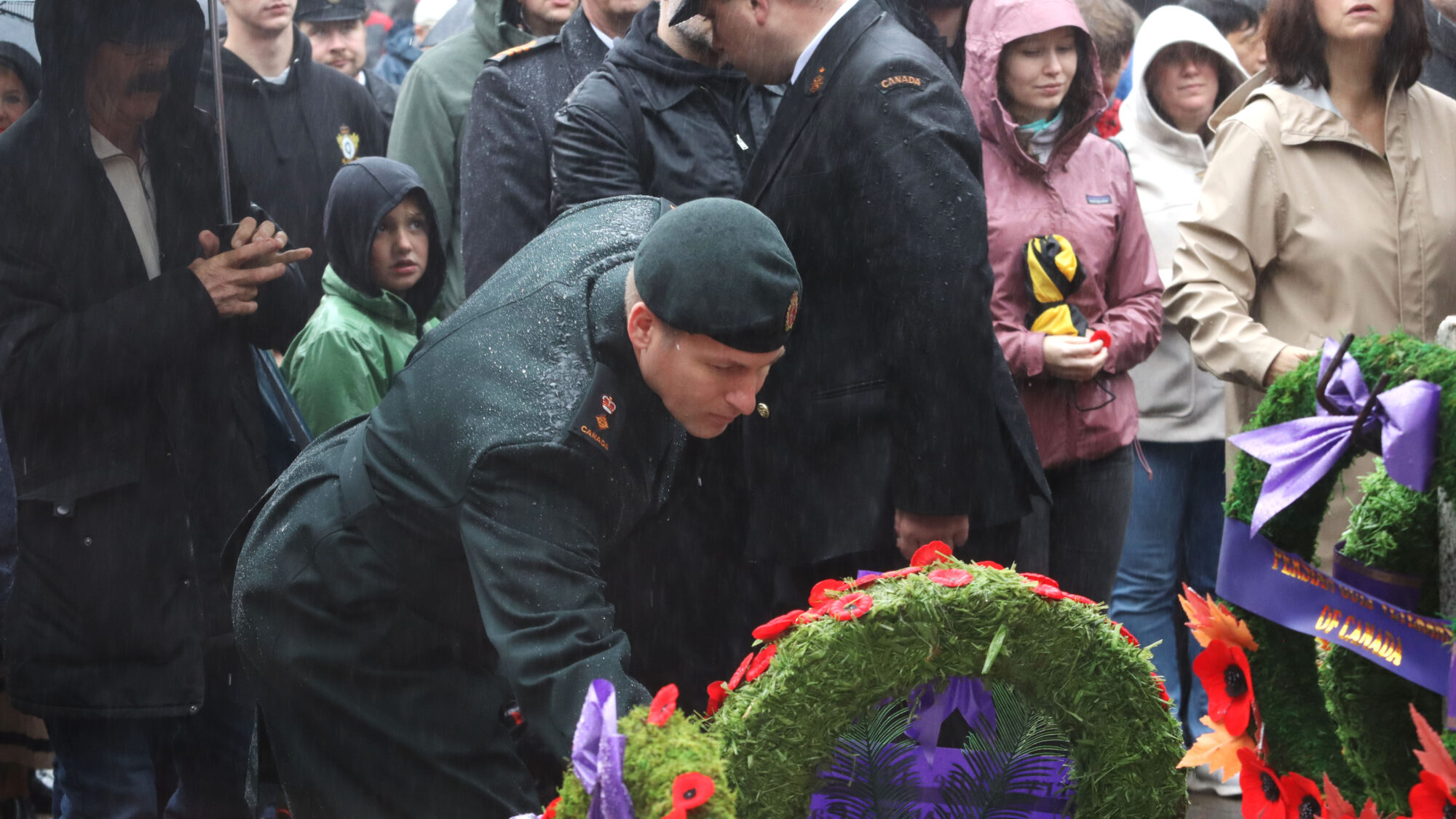 a soldier lays a poppy among a group of people