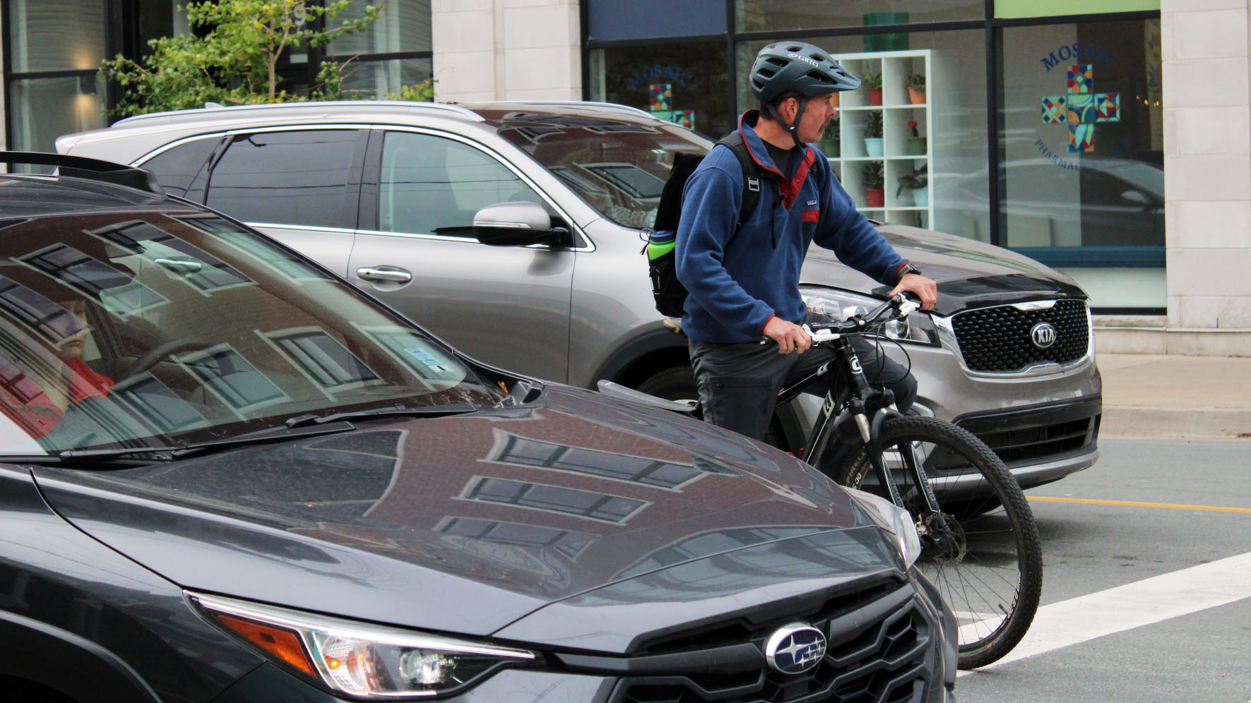 A person is biking through the street surrounded by cars.