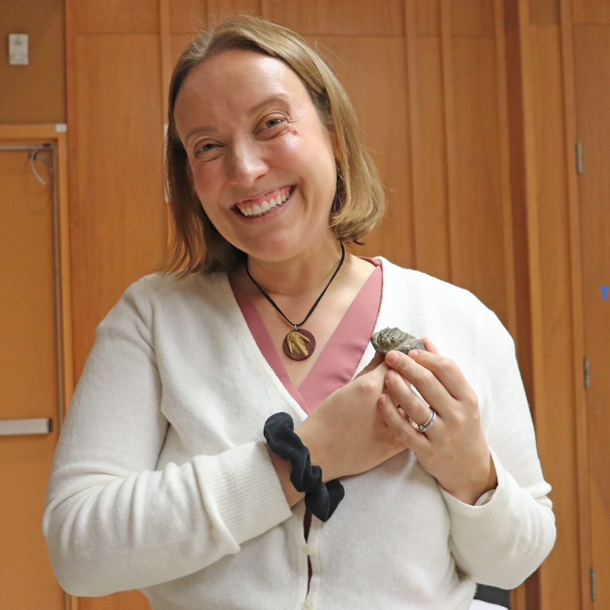 Geoscientist Catrina Russell-Dolan wears a necklace depicting a trilobite, and holding a real trilobite fossil in her hand on Sunday, Feb. 9th, 2025, at the Nova Scotia Museum of Natural History in Halifax. Trilobites are sea creatures that lived during the paleozoic era. Photo by Holly Lemmon