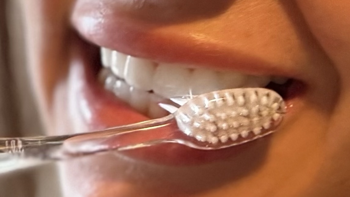 A close-up of a person's mouth while brushing their teeth.