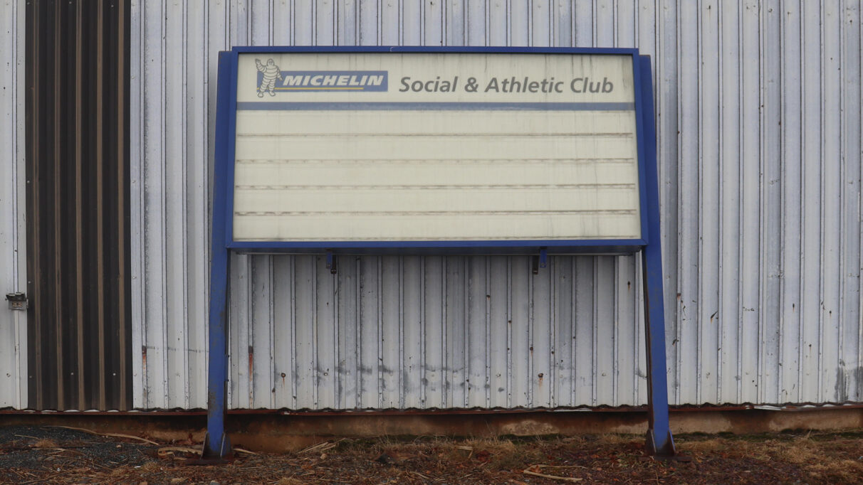 A dilapidated sign for the Michelin Social and Athletic Club leans against a metal wall in Bridgewater.