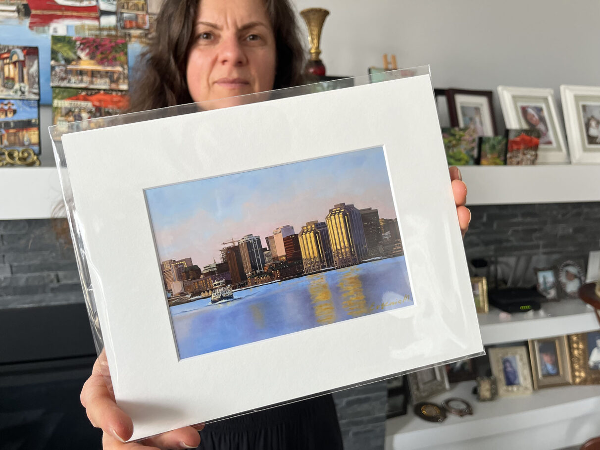 Evgenia Makogon poses with a small print of her painting Morning Ride at her home in Bedford, Nova Scotia, on Sunday, March 2, 2025.