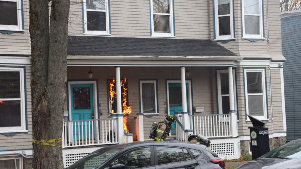 Fire fighters drag a waterhose into the door of a house on fire
