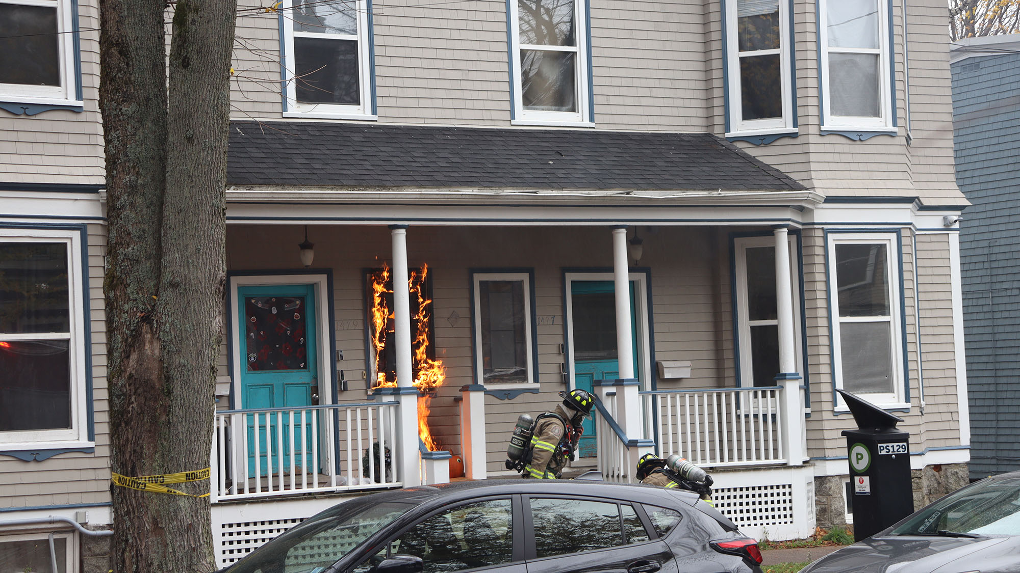 Fire fighters drag a waterhose into the door of a house on fire