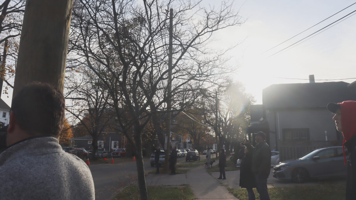 A crowd of people look off-camera to the church.