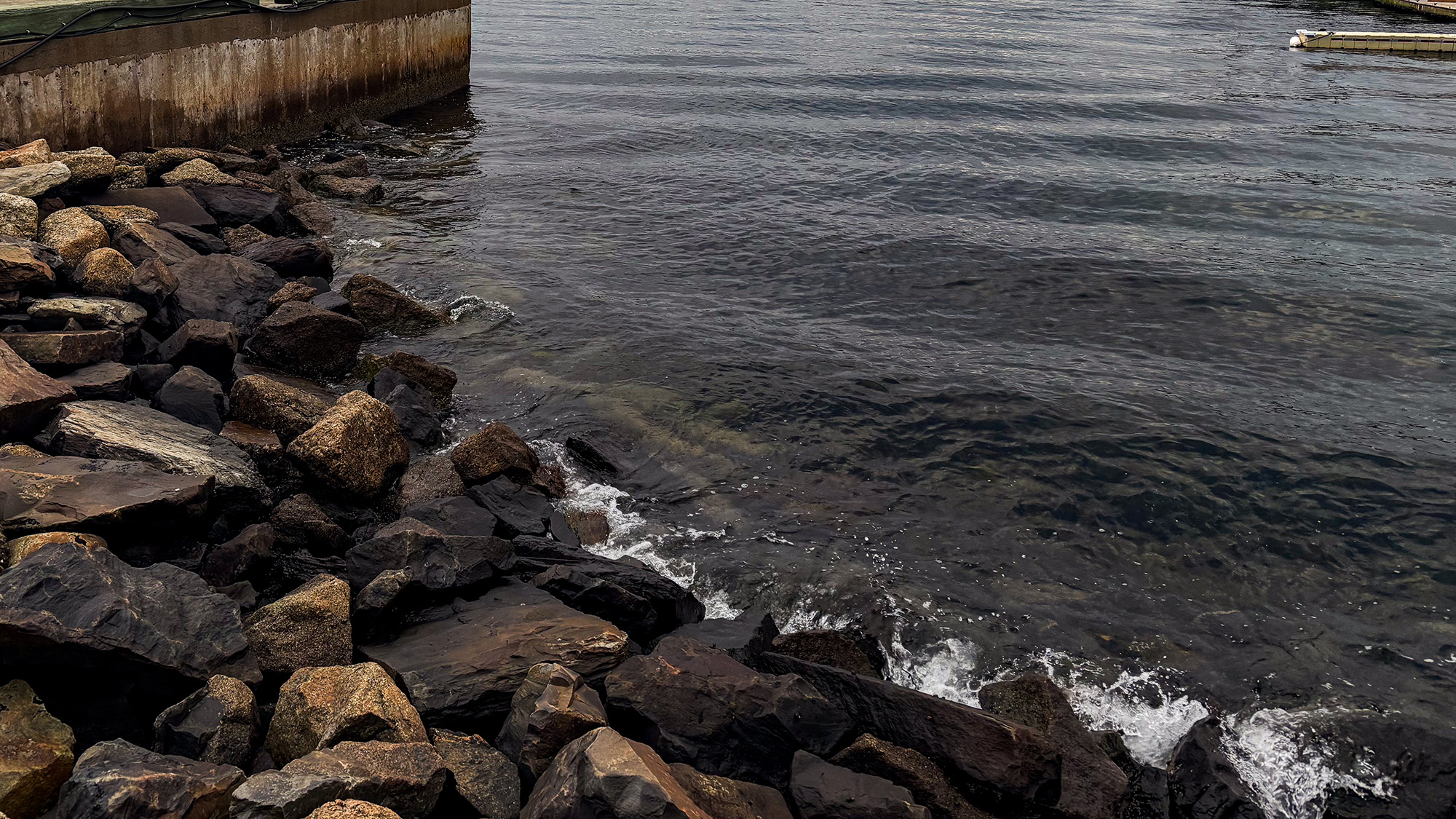 Tide water splashes against rocks in Halifax habrour.