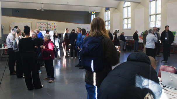 A crowd of people mill around a large room.