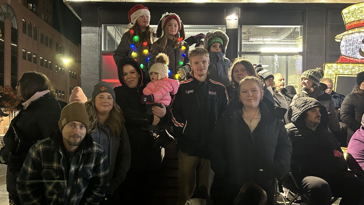 A family dressed in Santa Claus hats poses together for a photo.