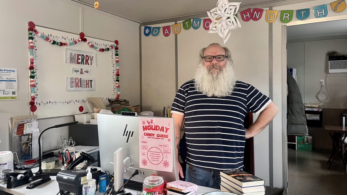 Man stands behind desk in library.