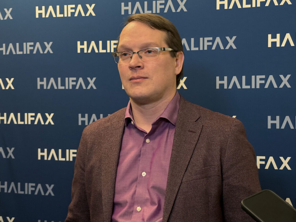 District 4 councilor Sam Austin stands in front of Halifax-branded wall, talking to reporters.