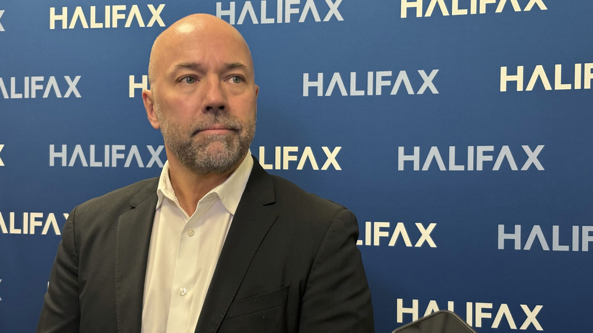 Mayor Andy Fillmore stands in front of a Halifax branded poster, speaking with journalists.