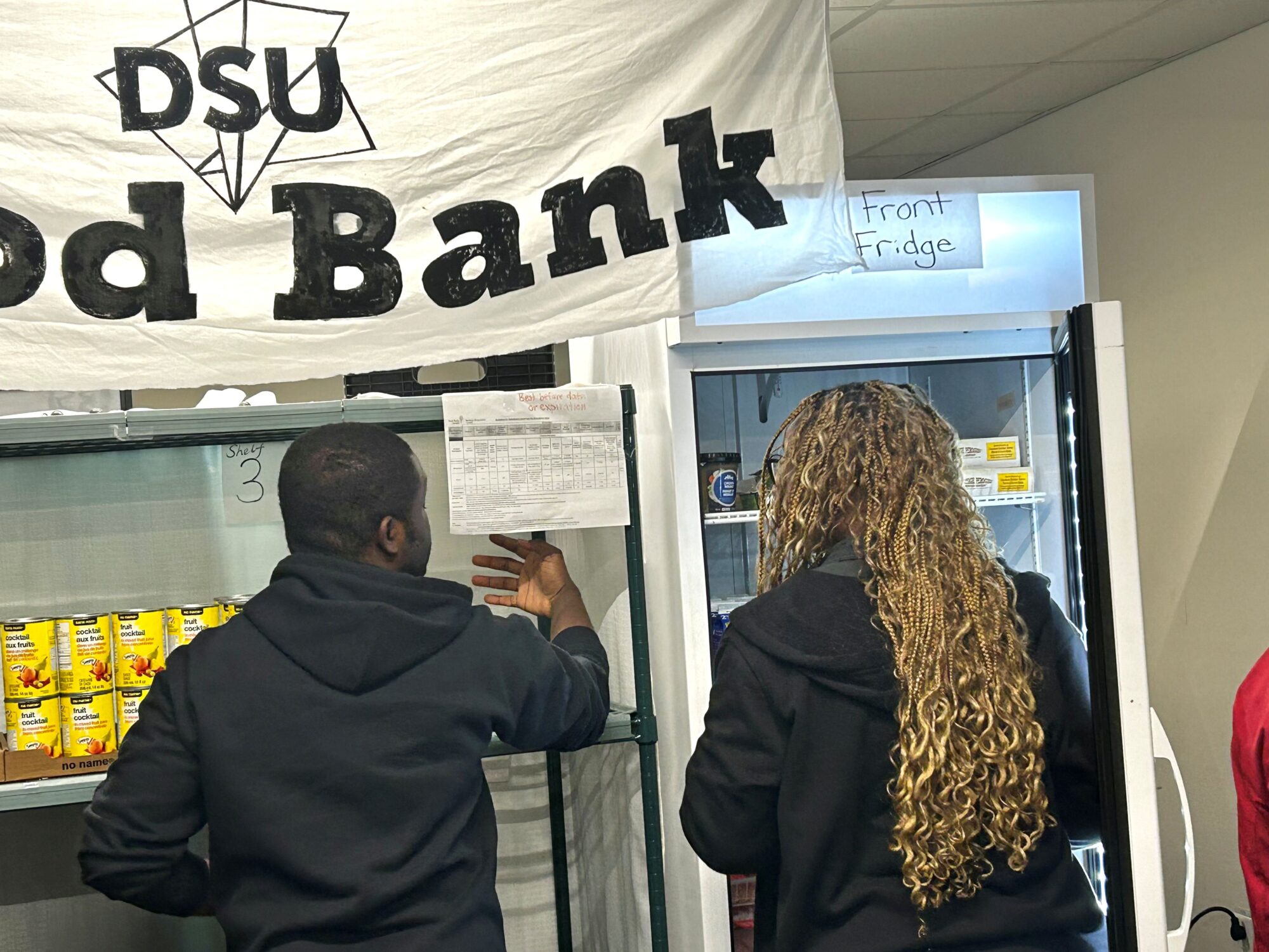 Akiwasi the Coordinator for the DSU Food Bank is helping out a student pick out food at the campus food bank.