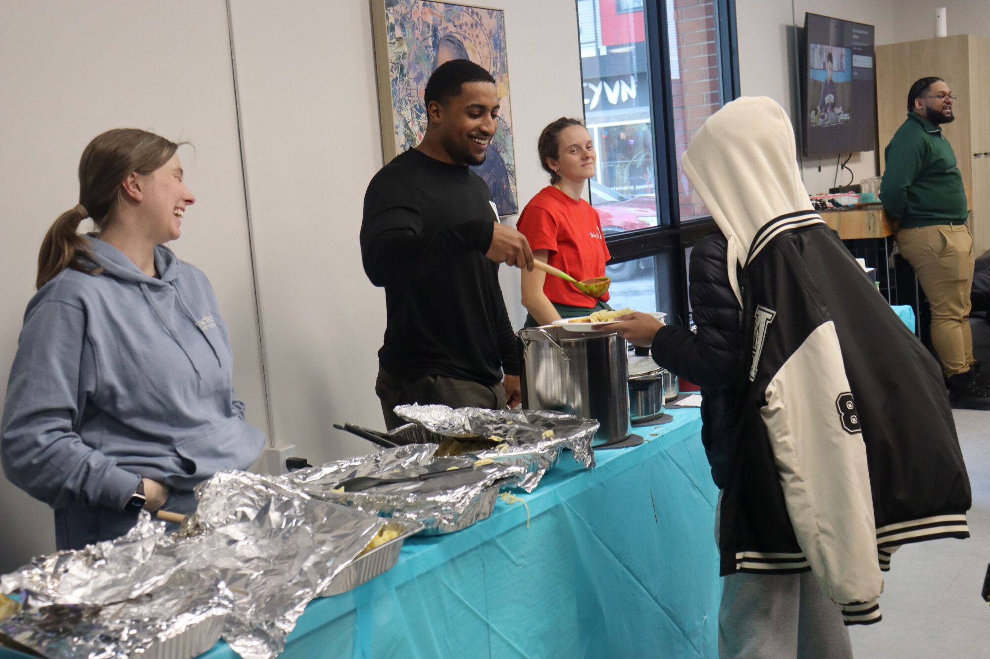 YMCA Staff is serving youth food and socializing with them at their Night of Nourishment Event.