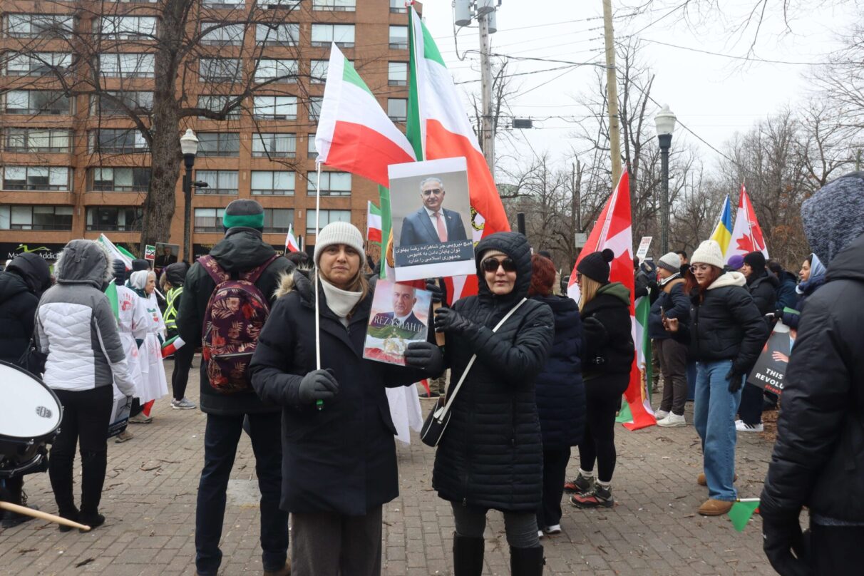 Sophie Molle, left, holding up a Persian flag and pictures of Prince Reza Pahlavi.