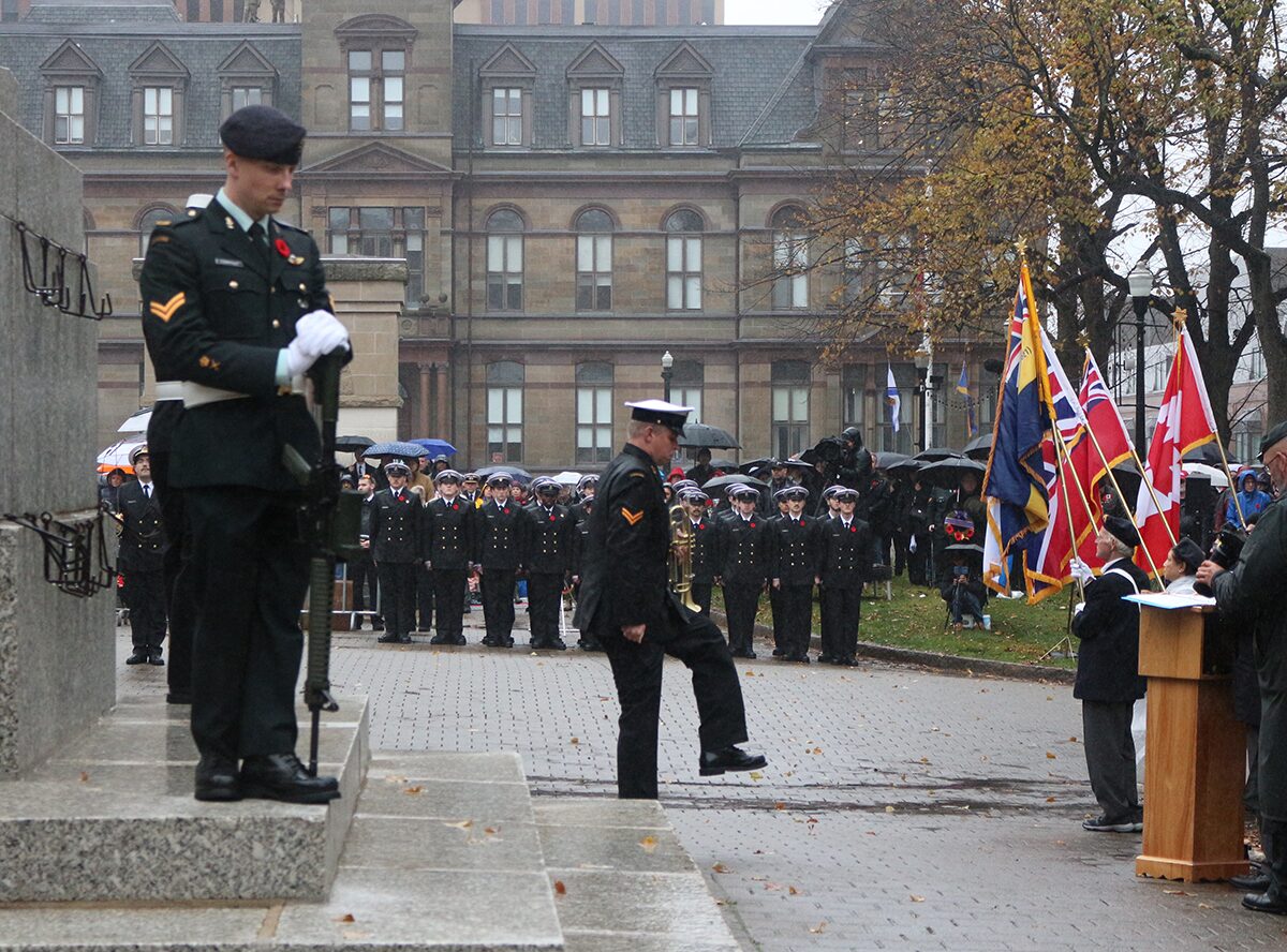 A soldier stands guard at the Halifax Grand Parade as another soldier marches past during the 2025 Remembrance Day ceremony.