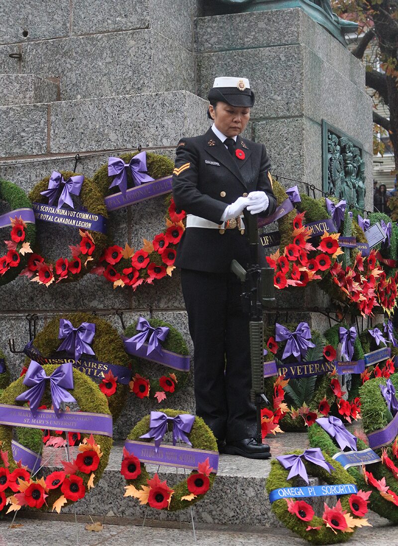 A female soldier stands guard surrounded by memorial wreaths and poppies at the Halifax Grand Parade for the 2025 Remembrance Day ceremony.