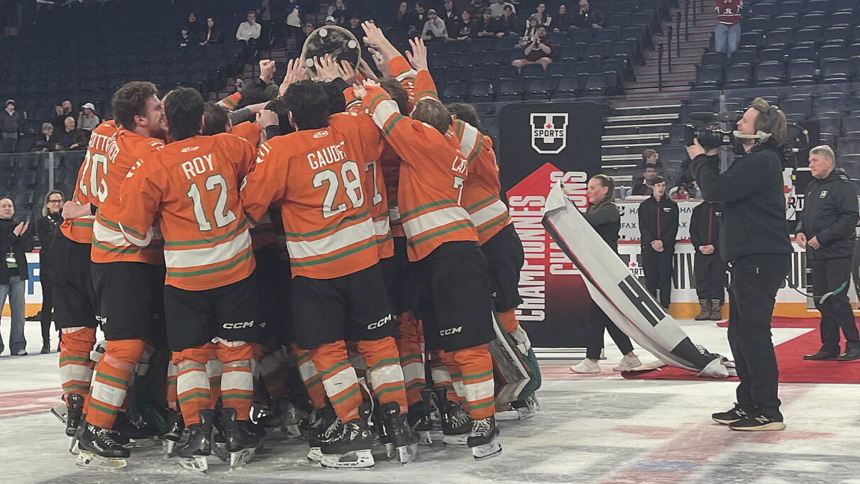 UQTR team huddles around Conor Frenette as he brings the David Johnston University Cup over to the team.