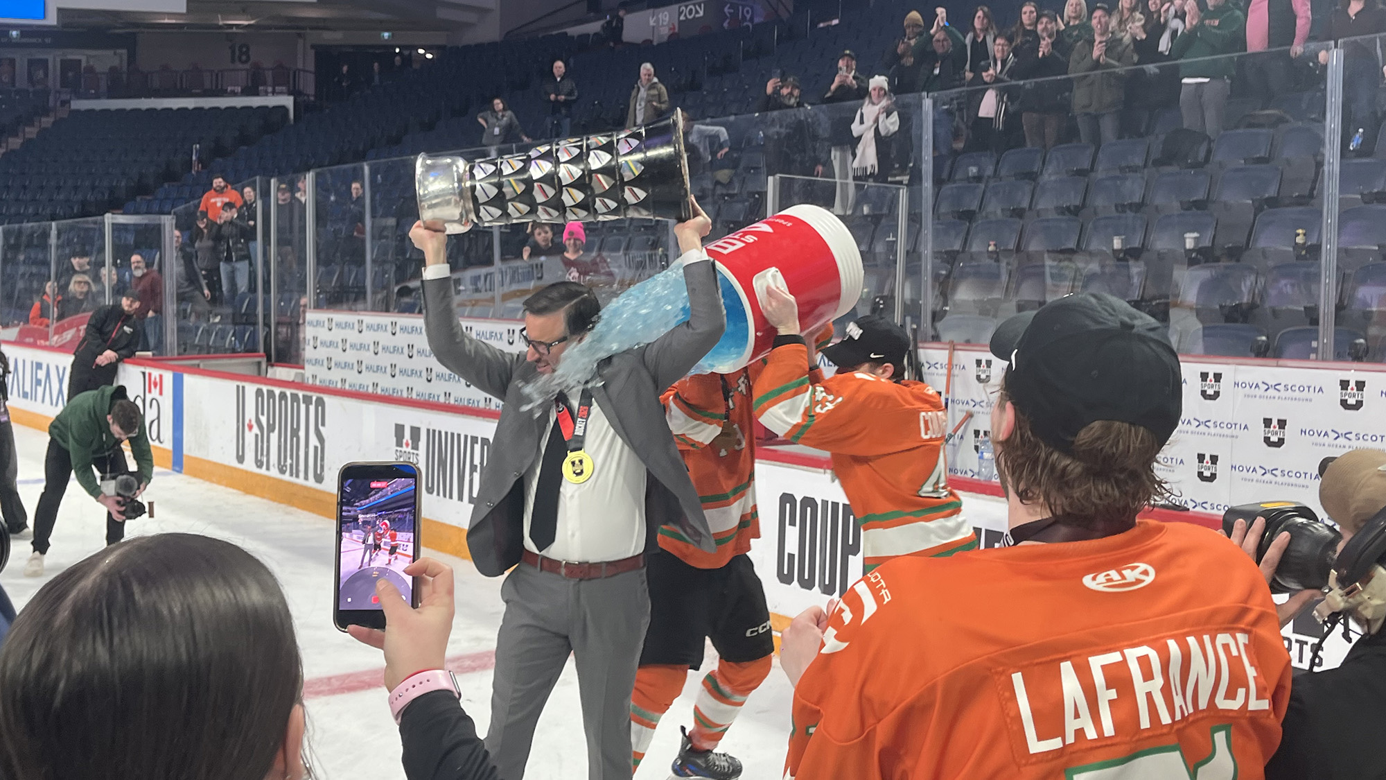 UQTR coach Marc-Étienne Hubert gets a blue sports drink poured on him while lifting the David Johnston University Cup.