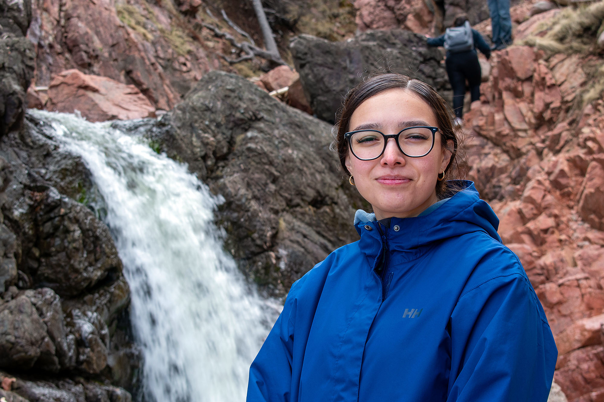 Morgan Denny stands in front of a waterfall by Kluskap’s Cave, May 2026.