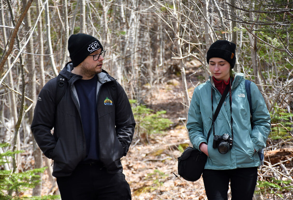 Tristen Simon, a project manager with Unama’ki Institute of Natural Resources, speaks to reporter Holly Lemmon while hiking to Kluskap Cave in Unama’ki/Cape Breton, N.S., May 2026.