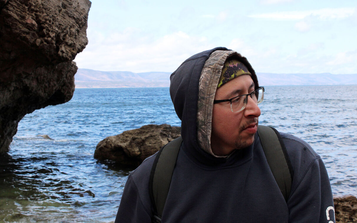 Bernard stands near the entrance to Kluscap’s Cave in Unama’ki, May 2026.